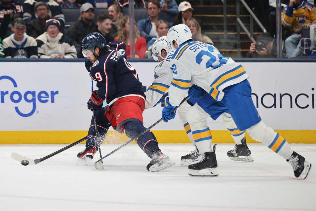 Columbus Blue Jackets defenseman Ivan Provorov, left, chases the puck in front of St. Louis Blues forward Dylan Holloway, center, and forward Pius Suter during the second period of an NHL hockey game in Columbus, Ohio, Saturday, Nov. 1, 2025. (AP Photo/Paul Vernon)