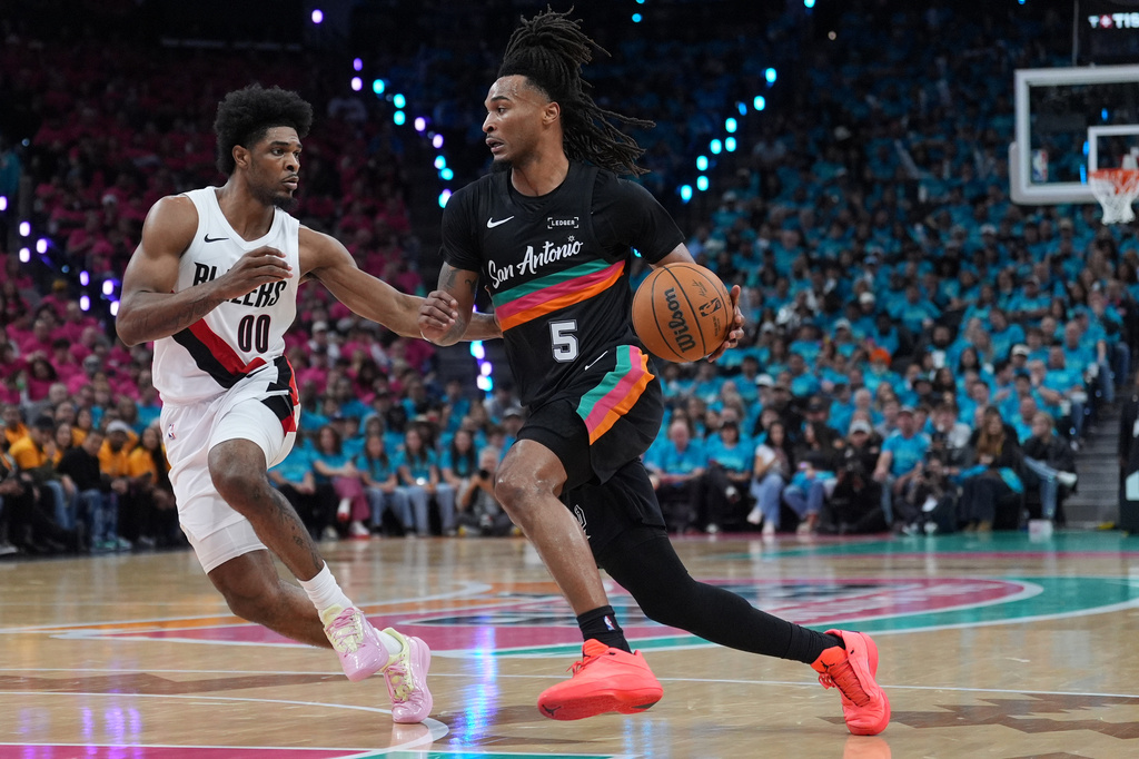 San Antonio Spurs guard Stephon Castle (5) drives against Portland Trail Blazers guard Scoot Henderson (00) during the second half in Game 1 of a first-round NBA playoffs basketball series in San Antonio, Sunday, April 19, 2026. (AP Photo/Eric Gay)