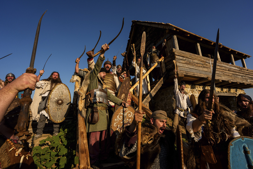 Members of historical reenactment groups wearing Dacian warrior outfits, scream before a battle in Poiana, Romania, Sunday, July 13, 2025, during the Getodava historical reenactment festival. (AP Photo/Andreea Alexandru)