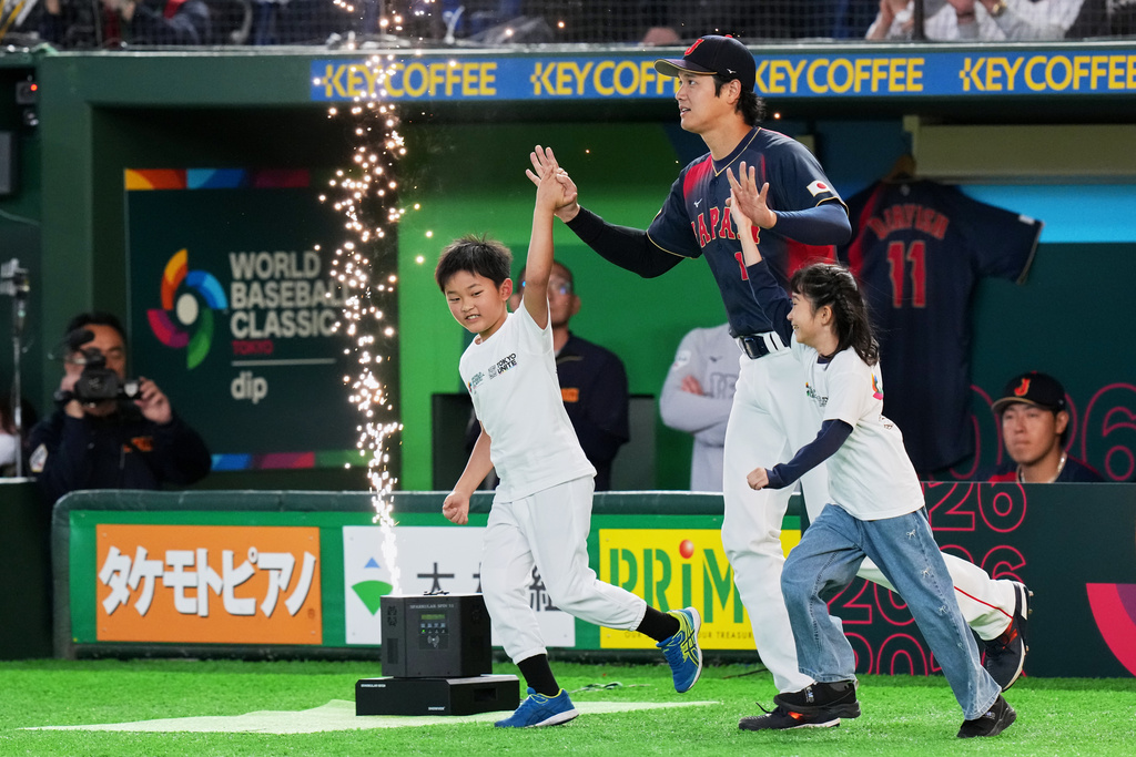 Japan's Shohei Ohtani enters the arena with young escorts before the start of a World Baseball Classic Pool C game between Japan and Taiwan Friday, March 6, 2026 in Tokyo. (AP Photo/Eugene Hoshiko)