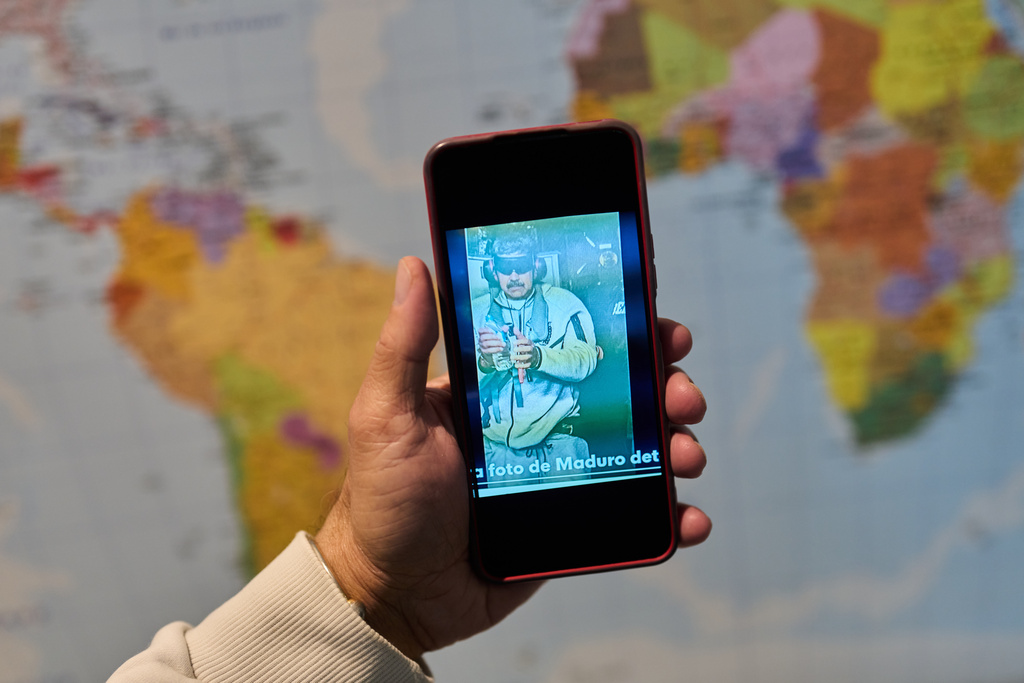 David Vallenilla holds a picture of deposed President Nicolas Maduro, blindfolded and handcuffed, during an interview with The Associated Press at his home in Madrid, Tuesday, Jan. 13, 2026. (AP Photo/Bernat Armangue)
