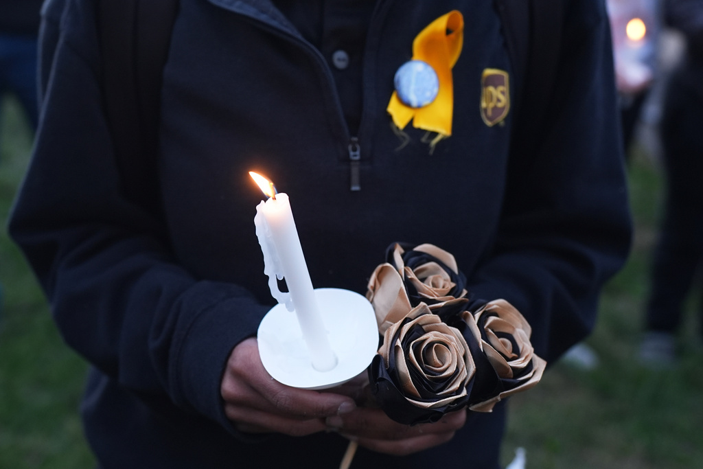 An attendee holds a candle and flowers during a vigil Thursday, Nov. 6, 2025, in Louisville, Ky., after a UPS plane crashed at Louisville Muhammad Ali International Airport. (AP Photo/Darron Cummings)