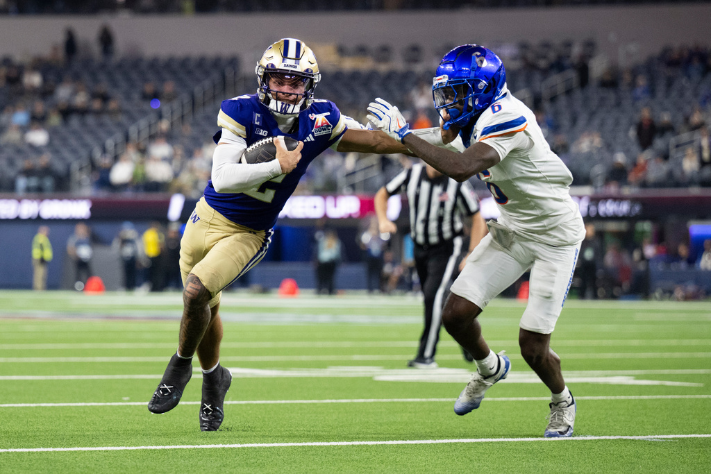 Washington quarterback Demond Williams Jr. (2) applies stiff arm to Boise State defensive back Jeremiah Earby (6) during the second half of the LA Bowl NCAA college football game Saturday, Dec. 13, 2025, in Inglewood, Calif. (AP Photo/Kyusung Gong)