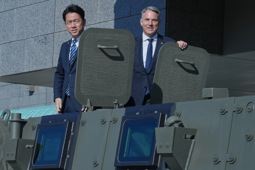 Japanese Minister of Defense Shinjiro Koizumi, left, and Australian counterpart Richard Marles, right, ride an Australian-made Bushmaster Mine Resistant Ambush Protected (MRAP) vehicle ahead of a bilateral meeting at the defense ministry Sunday, Dec. 7, 2025, in Tokyo. (AP Photo/Eugene Hoshiko, Pool)