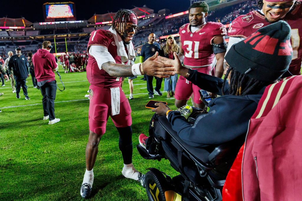 Florida State quarterback Tommy Castellanos (1) celebrates with gunshot-wounded linebacker Ethan Pritchard, right, after an NCAA college football game against Virginia Tech, Saturday, Nov. 15, 2025, in Tallahassee, Fla. (AP Photo/Colin Hackley)