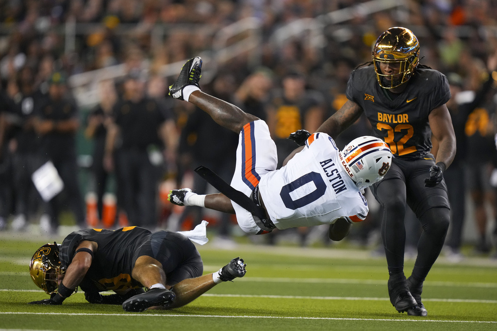 Auburn running back Damari Alston (0) is tripped up by Baylor safety Jacob Redding, left, during the second half of an NCAA college football game Friday, Aug. 29, 2025, in Waco, Texas. (AP Photo/Julio Cortez)