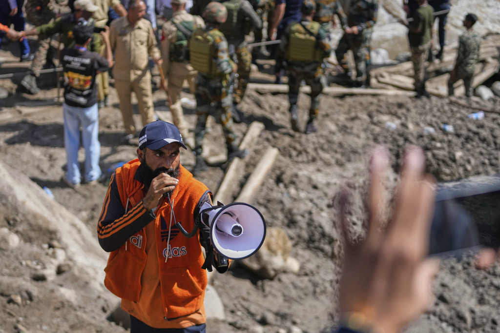 A volunteer asks residents and tourists to stay calm as local authorities carry out rescue operations after Thursday's flash floods in Chositi village, Kishtwar district, Indian-controlled Kashmir, Saturday, Aug. 16, 2025. (AP Photo/Channi Anand)