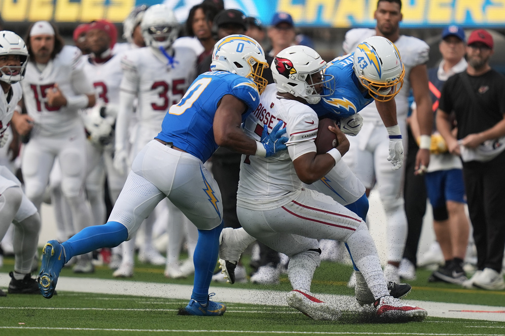 Arizona Cardinals quarterback Jacoby Brissett, middle, is hit by Los Angeles Chargers linebacker Daiyan Henley (0) and linebacker Troy Dye (43) during the second half of an NFL football game, Sunday, Sept. 13, 2026, in Inglewood, Calif. (AP Photo/Gregory Bull)