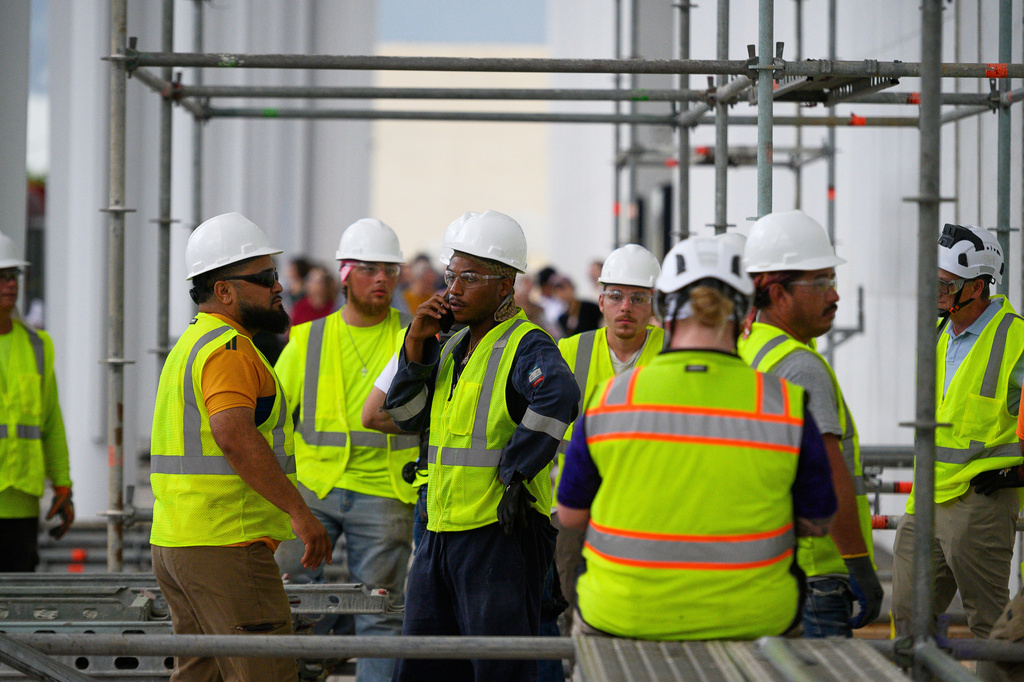 Workers wait for the rain to stop before resuming work to remove President Donald Trump's name from the John F. Kennedy Center for the Performing Arts in Washington, Friday, June 12, 2026. (AP Photo/Cliff Owen)