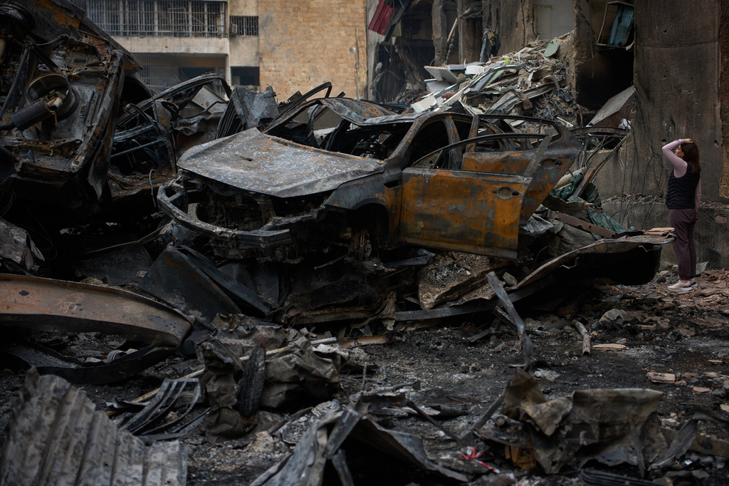A resident checks damage to buildings as she walks near charred cars, at the site of Wednesday's Israeli airstrike, in Beirut, Lebanon, Friday, April 10, 2026. (AP Photo/Emilio Morenatti)