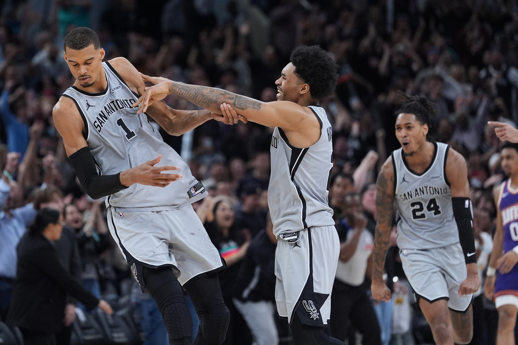 San Antonio Spurs forward Victor Wembanyama (1) dis celebrated by teammates guard Dylan Harper, center, and guard Devin Vassell (24) after he hit a game-winning score against the Phoenix Suns in the final seconds of an NBA basketball game in San Antonio, Thursday, March 19, 2026. (AP Photo/Eric Gay)