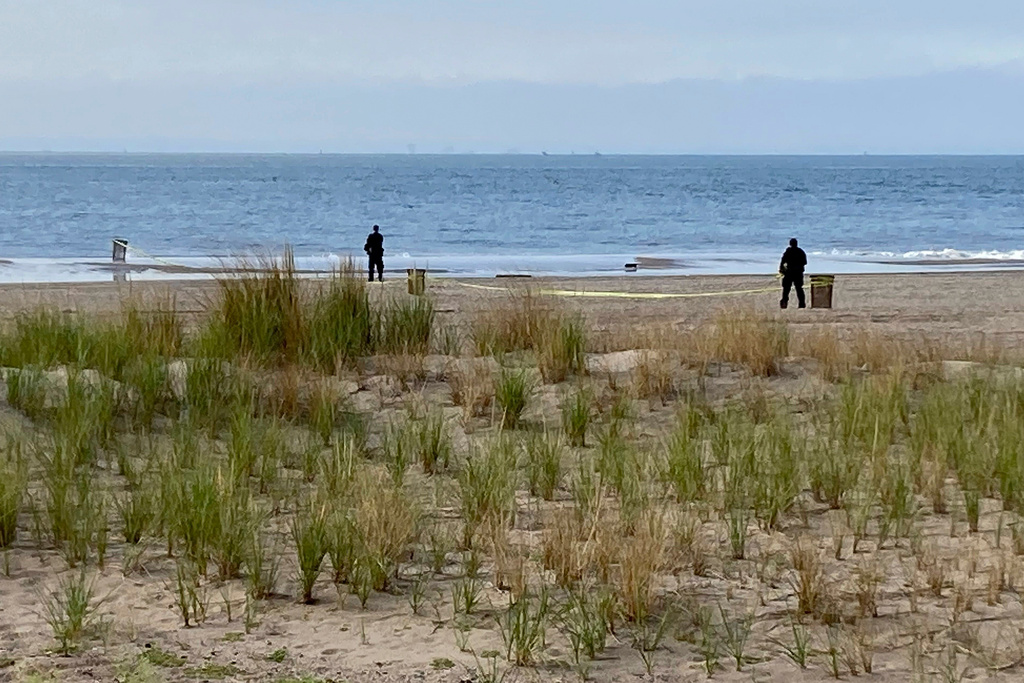 FILE - New York Police investigators examine a stretch of beach at Coney Island where three children were found dead in the surf, Sept. 12, 2022, in New York. (AP Photo/Joseph Frederick, File)