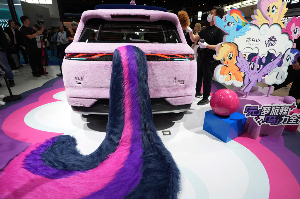 A worker dust the purple fur of a car decorated to look like a purple unicorn at the BYD booth during Auto China 2026 in Beijing, Friday, April 24, 2026. (AP Photo/Ng Han Guan)