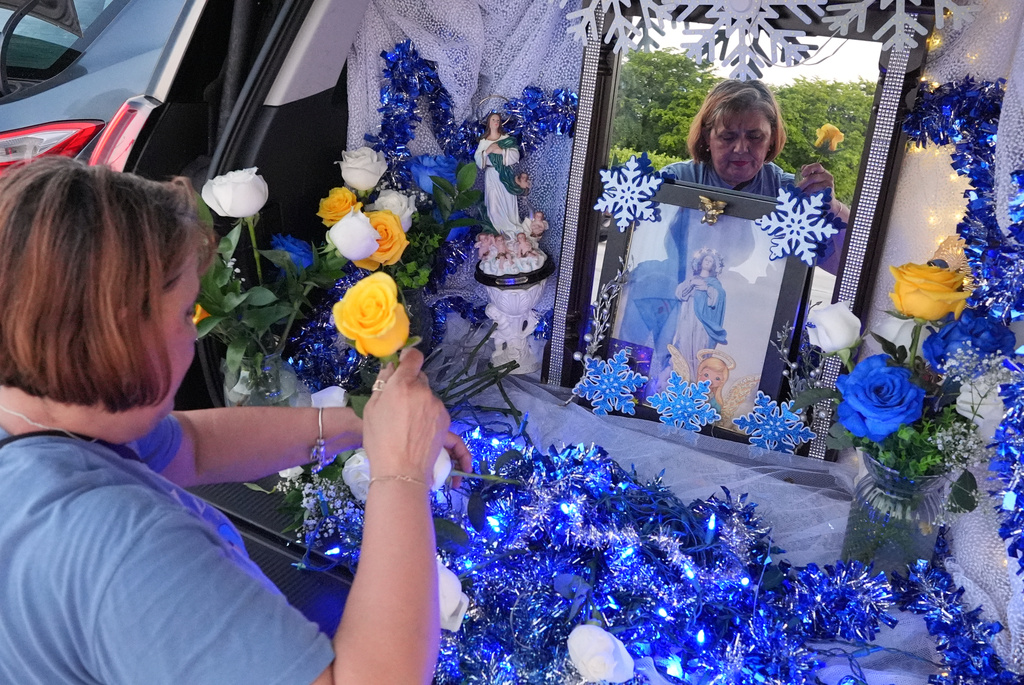 Egda Lee sets up an altar centered around a picture of the Virgin Mary which she carried with her when she crossed the U.S. border in 1984 pregnant with her son Neri Flores, as Nicaraguan parishioners of St. John Bosco Catholic Church celebrate the Dec. 8 feast of the Immaculate Conception, Sunday, Dec. 7, 2025, in Miami. (AP Photo/Rebecca Blackwell)