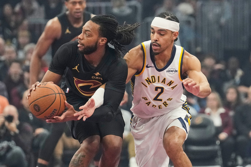 Indiana Pacers guard Andrew Nembhard (2) reaches for the ball held by Cleveland Cavaliers guard Darius Garland, left, in the first half of an NBA Cup basketball game Friday, Nov. 21, 2025, in Cleveland. (AP Photo/Sue Ogrocki)
