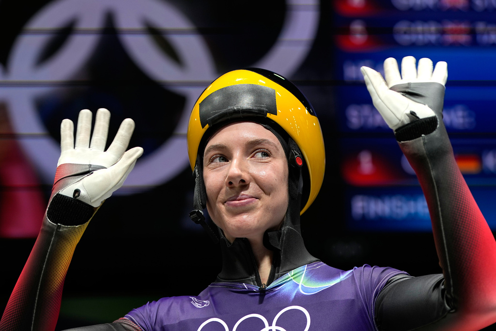 Germany's Susanne Kreher waves as she arrives at the finish during a women's skeleton run at the 2026 Winter Olympics, in Cortina d'Ampezzo, Italy, Friday, Feb. 13, 2026. (AP Photo/Alessandra Tarantino)