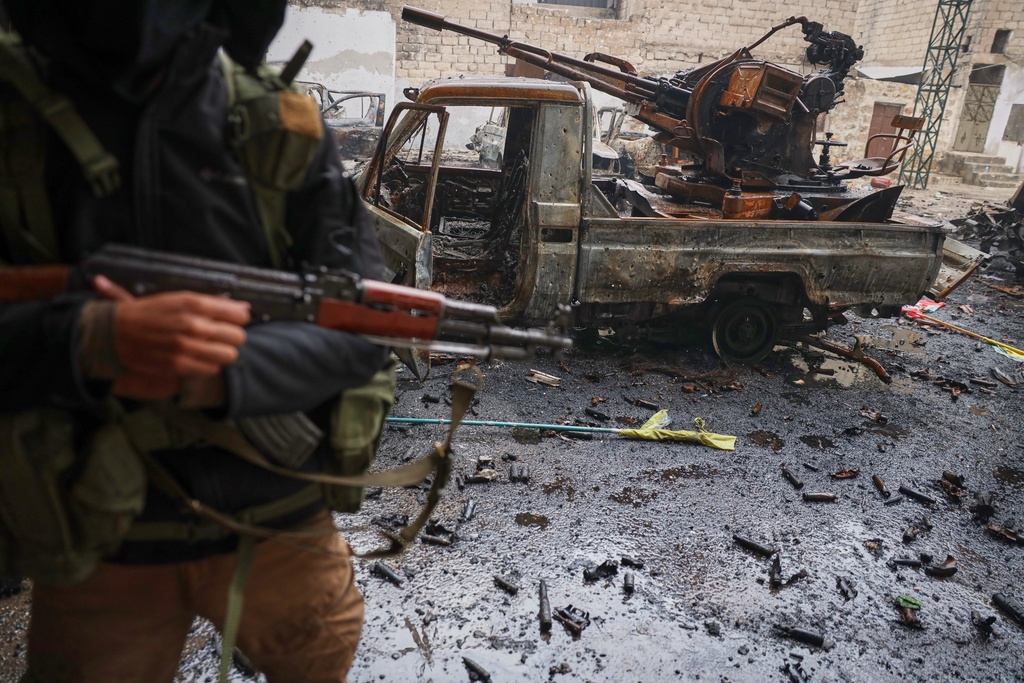FILE - A member of Syrian security forces stands next to a destroyed vehicle in the predominantly Kurdish Sheikh Maqsoud neighborhood where clashes broke out Tuesday Jan. 6 between government forces and the Kurdish-led Syrian Democratic Forces in the northern city of Aleppo, Syria, Monday, Jan. 12, 2026. (AP Photo/Omar Albam, File)