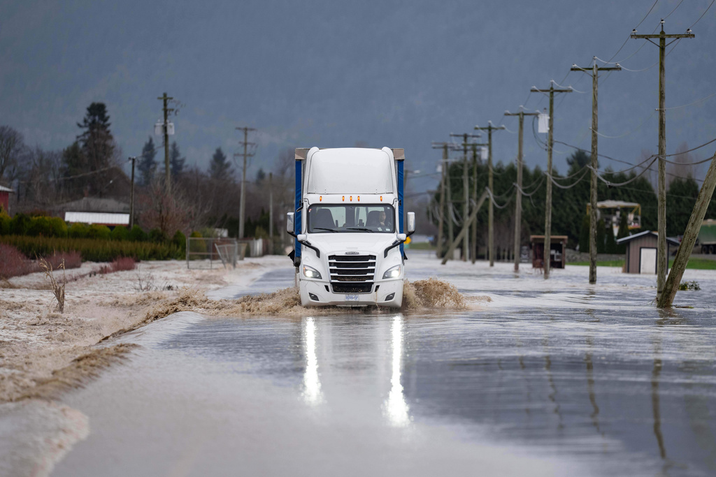 A semi-truck crosses a flooded street in Abbotsford, British Columbia, on Thursday, Dec. 11, 2025. (Ethan Cairns/The Canadian Press via AP)