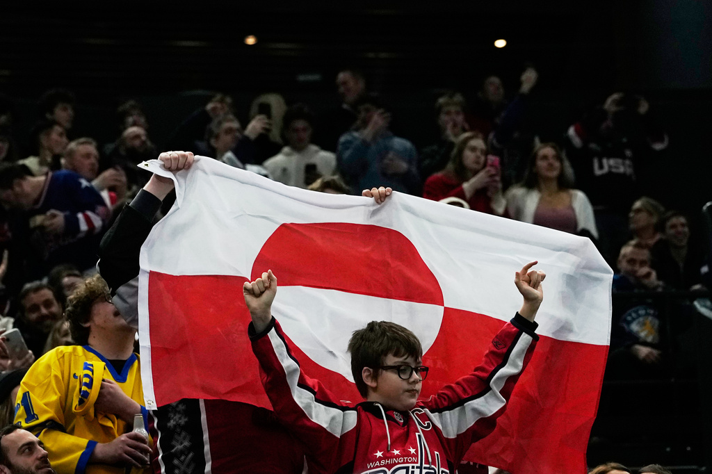 Fans hold Greenland national flag before a preliminary round match of men's ice hockey between United States and Denmark at the 2026 Winter Olympics, in Milan, Italy, Saturday, Feb. 14, 2026. (AP Photo/Petr David Josek)