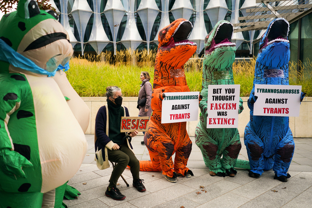 Demonstrators in costumes hold placards during a protest outside the U.S. embassy, in London, Saturday, Oct. 18, 2025.(AP Photo/Alberto Pezzali)
