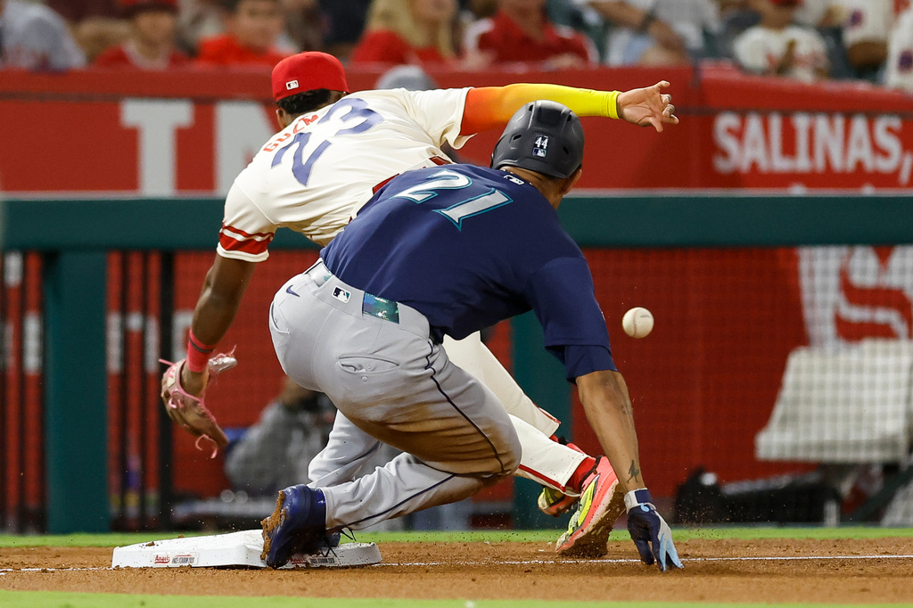 Seattle Mariners' Julio Rodriguez, front, runs to third base as Los Angeles Angels third baseman Denzer Guzman, back, reaches for the ball during the sixth inning of a baseball game Tuesday, Sept. 15, 2026, in Anaheim, Calif. (AP Photo/Caroline Brehman)