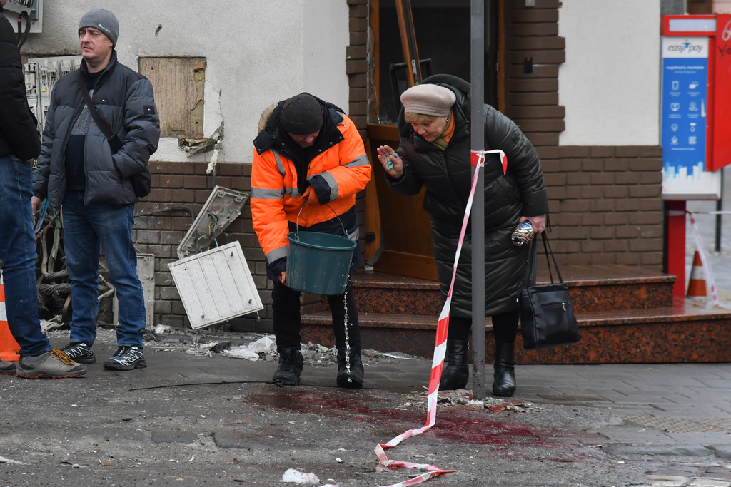 A municipal worker tries to wipe away bloodstains at the site of what authorities are describing as a "terrorist' attack" in central Lviv, Ukraine, Sunday, Feb. 22, 2026. (AP Photo/Mykola Tys)