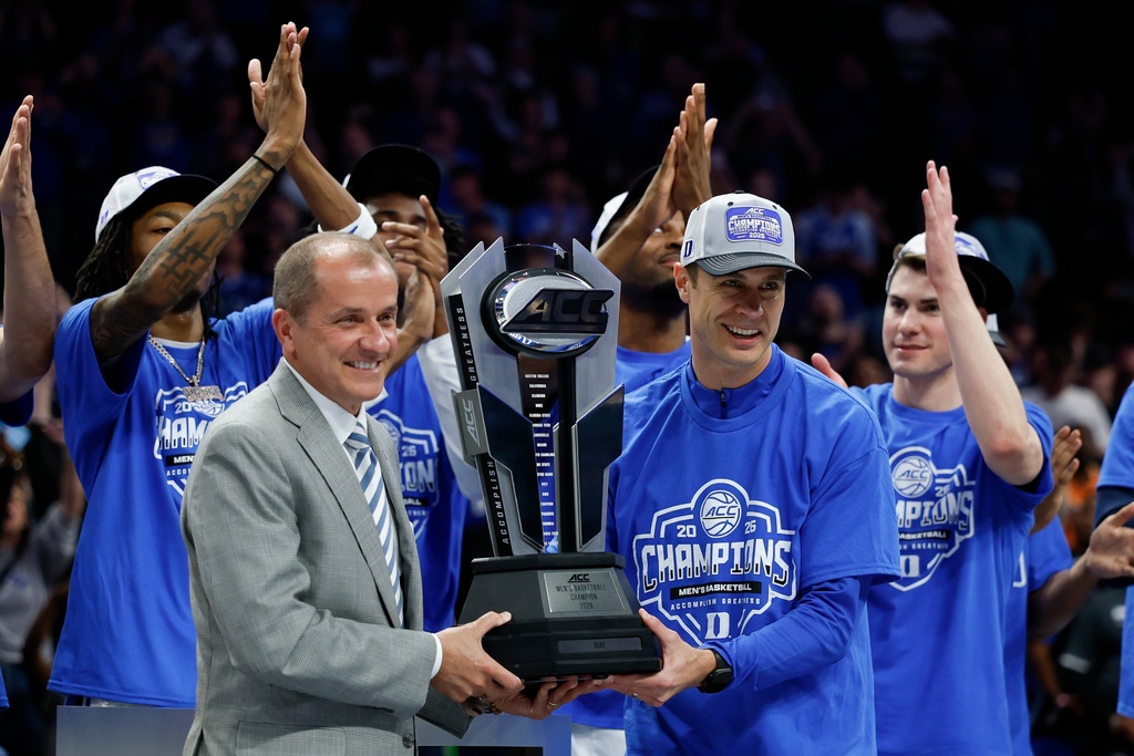 Jim Phillips presents Duke head coach Jon Scheyer with the trophy as Duke wins the championship of the Atlantic Coast Conference tournament in an NCAA college basketball game in Charlotte, N.C., Saturday, March 14, 2026. (AP Photo/Nell Redmond)