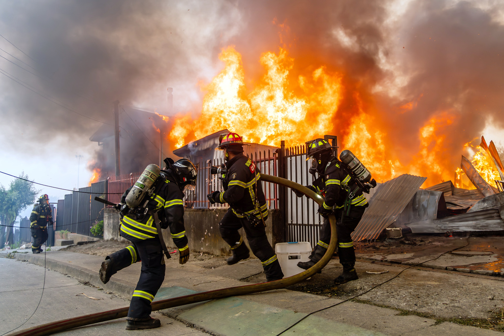 Firefighters battle a blaze at a house as wildfires burn in Lirquen, Chile, Sunday, Jan. 18, 2026. (AP Photo/Javier Torres)