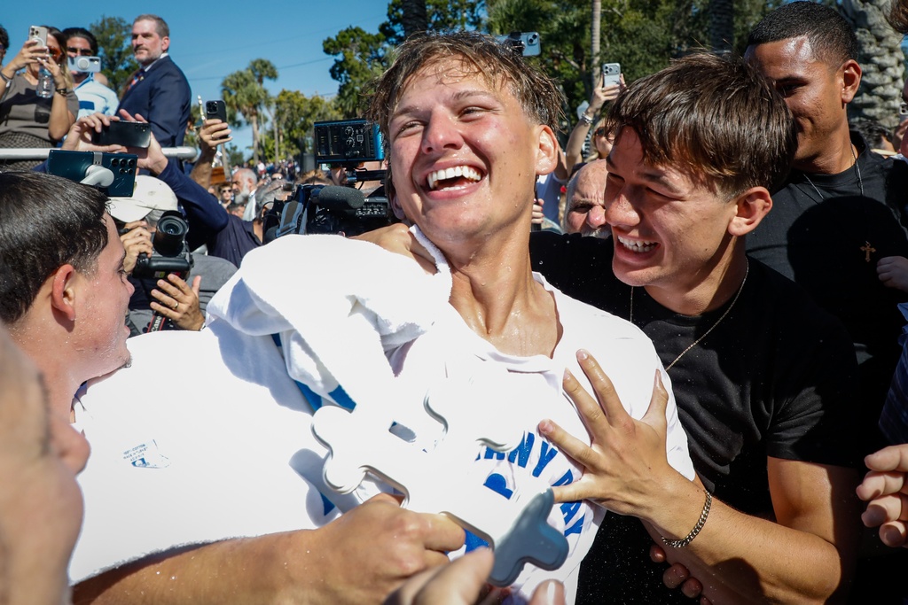 Athos Karistinos, 18, of Tarpon Springs, is congratulated by cross divers, friends and family, after he retrieves the cross during the annual cross dive in the Spring Bayou, part of the Epiphany celebration on Tuesday, Jan. 6, 2026, in Tarpon Springs, Fla. (Jefferee Woo /Tampa Bay Times via AP)