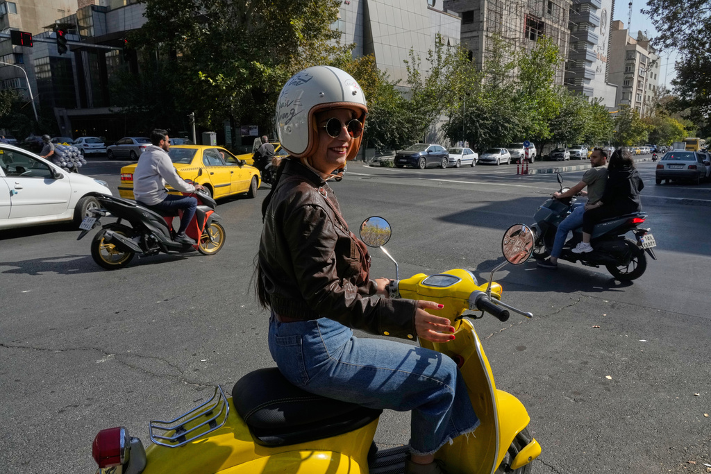 Iranian woman Merat Behnam speaks on her motorbike in downtown Tehran, Iran, Saturday, Nov. 1, 2025. (AP Photo/Vahid Salemi)