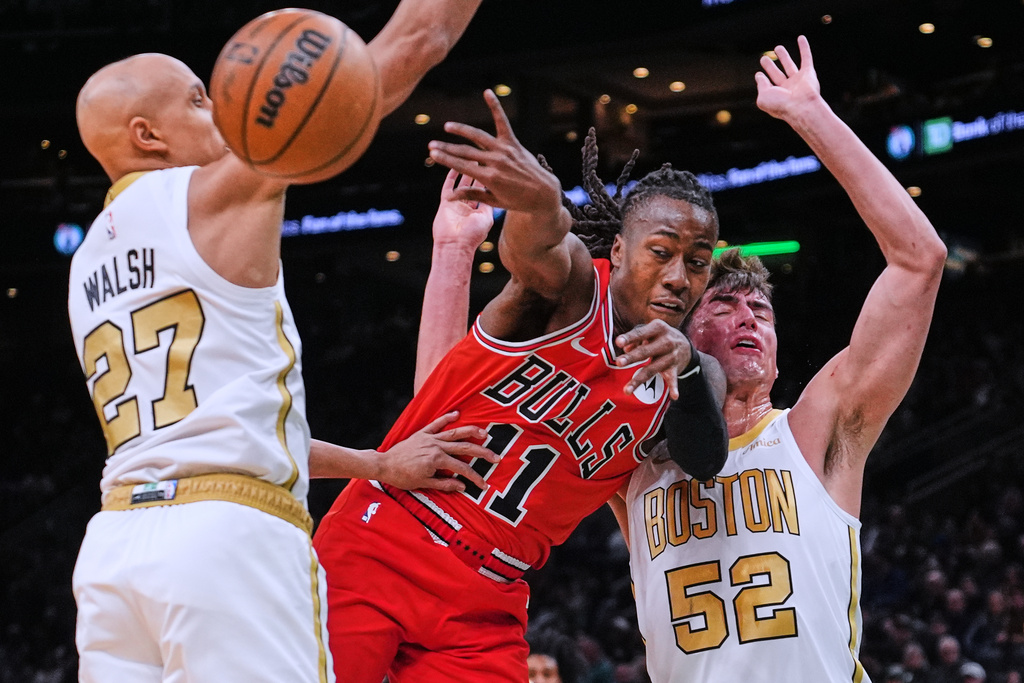 Chicago Bulls guard Ayo Dosunmu (11) passes the ball while covered by Boston Celtics guard Jordan Walsh (27) and center Luka Garza (52) during the first half of an NBA basketball game, Monday, Jan. 5, 2026, in Boston. (AP Photo/Charles Krupa)