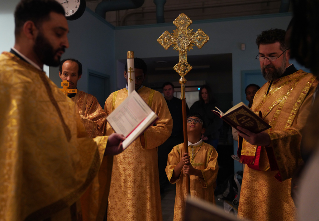 Thomas Abernathy, 8, looks up at the cross as his father, the Rev. Paul Abernathy, left, performs a Chrismation service at St. Moses the Black Orthodox Church, Sunday, Nov. 9, 2025, in Pittsburgh. (AP Photo/Jessie Wardarski)