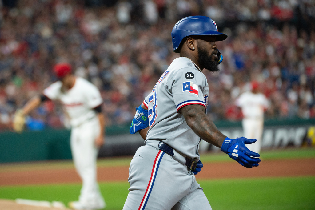 Texas Rangers' Adolis Garcia, foreground, rounds the bases after hitting a solo home run off Cleveland Guardians relief pitcher Joey Cantillo, rear, during the fourth inning of a baseball game, Saturday, Sept. 27, 2025, in Cleveland. (AP Photo/Phil Long)