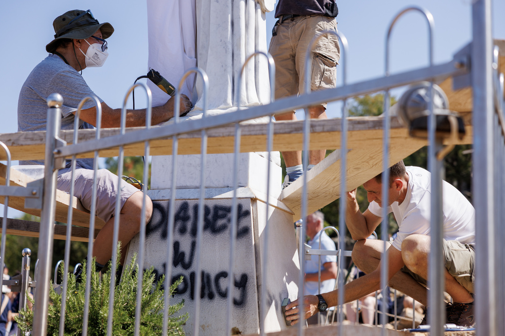 Volunteers clean the vandalized statue of the Virgin Mary, which has been covered with a white sheet, on Apparition Hill in Medjugorje, Bosnia, Tuesday, July 28, 2026. (AP Photo)