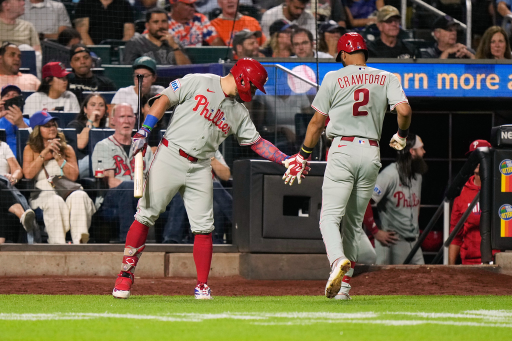 Philadelphia Phillies' Kyle Schwarber, left, greets Justin Crawford (2) after Crawford hit a sac fly during the eighth inning of a baseball game against the New York Mets, Thursday, Sept. 17, 2026, in New York. (AP Photo/Seth Wenig)