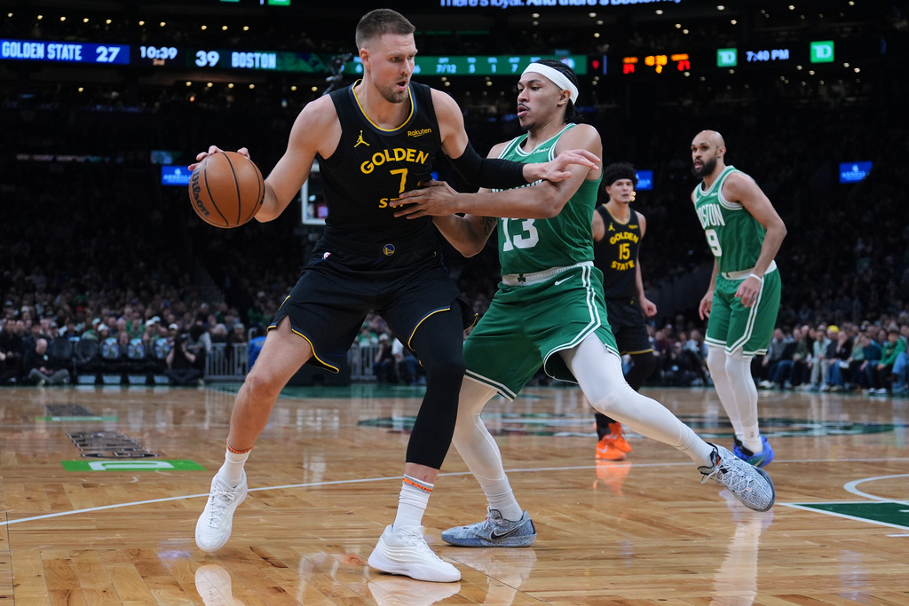 Golden State Warriors center Kristaps Porzingis (7) drives to the basket against Boston Celtics guard Ron Harper Jr. (13) during the first half of an NBA basketball game, Wednesday, March 18, 2026, in Boston. (AP Photo/Charles Krupa)
