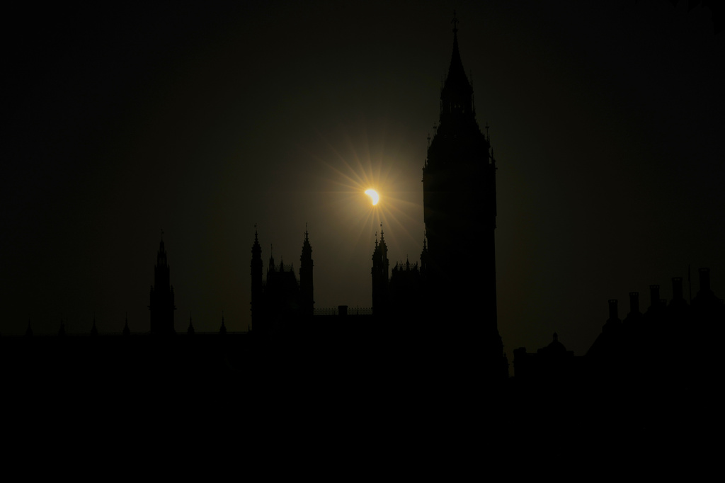 A partial solar eclipse is seen above the Houses of Parliament in London, Wednesday, Aug. 12, 2026. (AP Photo/Kin Cheung)