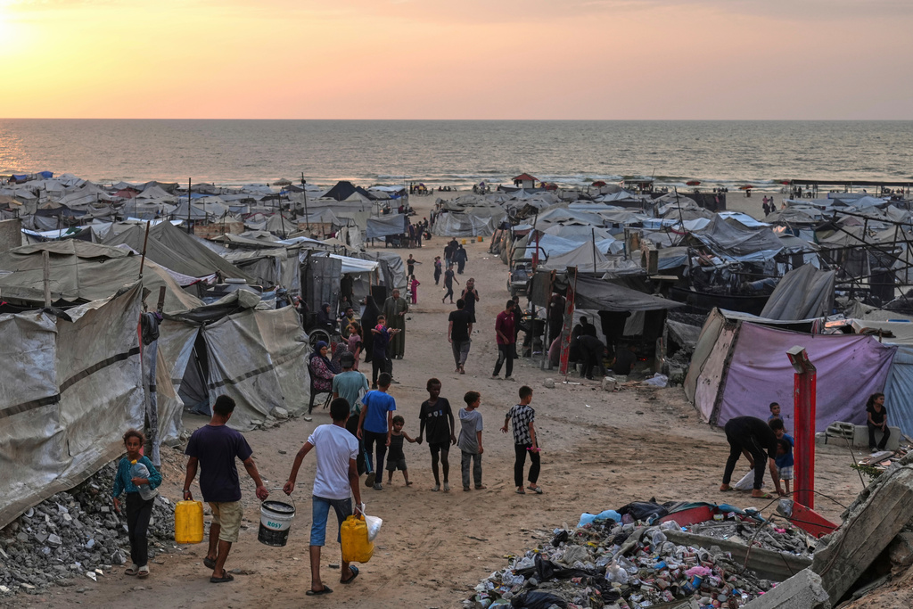 Displaced Palestinians walk through a makeshift camp along the beach in Gaza City, Sunday, Aug. 10, 2025. (AP Photo/Jehad Alshrafi)