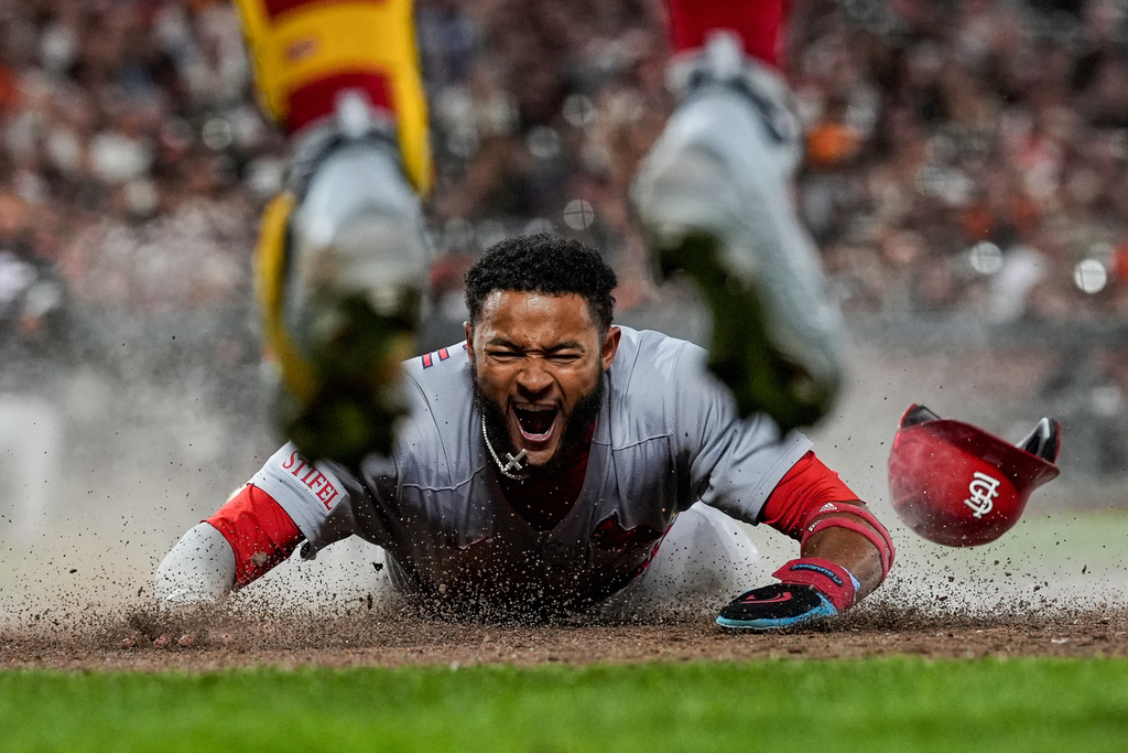 St. Louis Cardinals' Victor Scott II, bottom, scores against the San Francisco Giants on Brendan Donovan's double during the ninth inning of a baseball game, Sept. 23, 2025, in San Francisco. (AP Photo/Godofredo A. Vásquez, File)