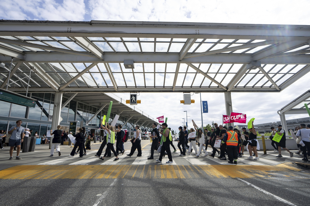 Picketers march around the departures level at the Vancouver International Airport in Richmond, British Columbia, Sunday, Aug. 17, 2025. (Ethan Cairns/The Canadian Press via AP)