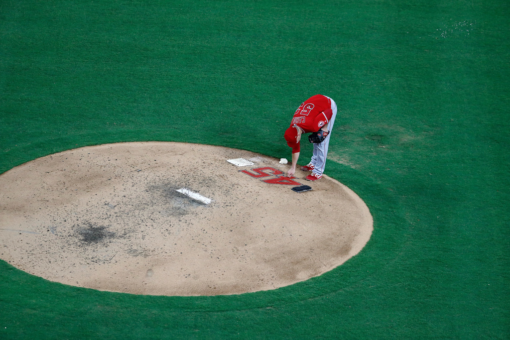 FILE - Los Angeles Angels relief pitcher Trevor Cahill reaches down to touch the number 45 on the back of the mound as he prepares to work against the Texas Rangers in the fifth inning of a baseball game in Arlington, Texas, July 2, 2019. (AP Photo/Tony Gutierrez, File)