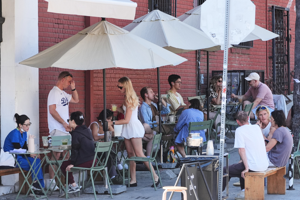 People gather outside of a cafe on a unseasonably hot day Tuesday, Oct. 28, 2025, in Los Angeles. (AP Photo/Damian Dovarganes)