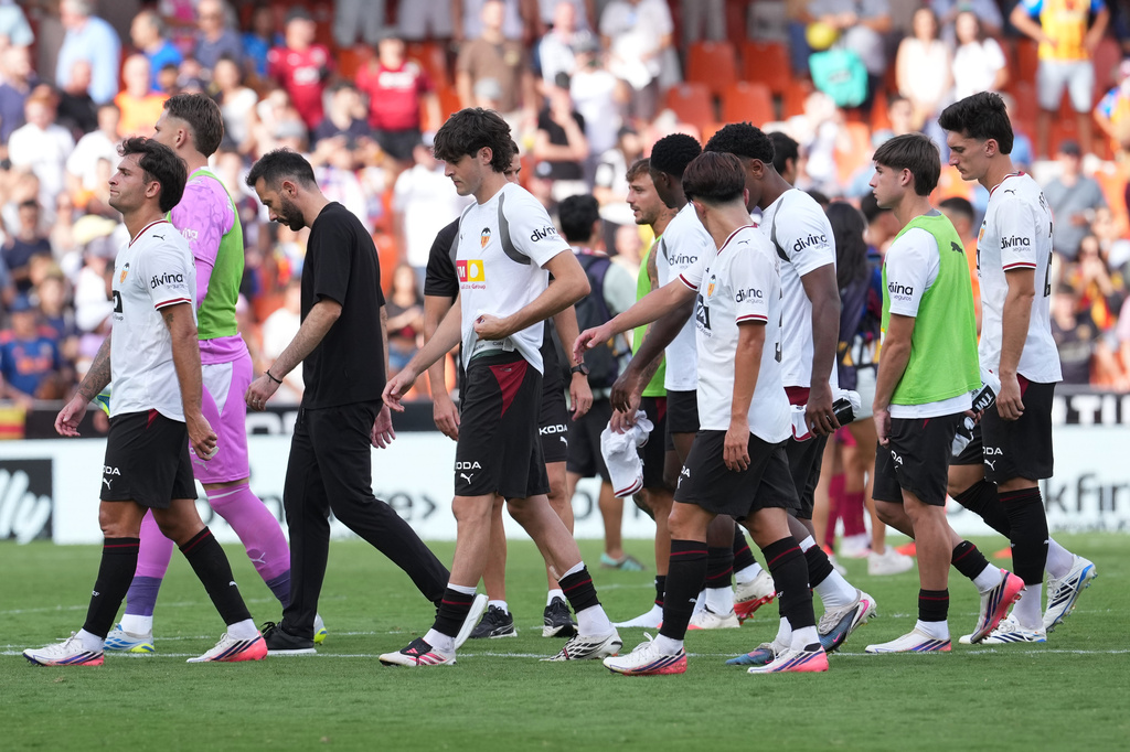 Valencia's head coach Carlos Corberan, third left, and players leave the field after their loss in the Spanish La Liga soccer match against Barcelona in Valencia, Spain, Sunday, Sept. 6, 2026. (AP Photo/Alberto Saiz)