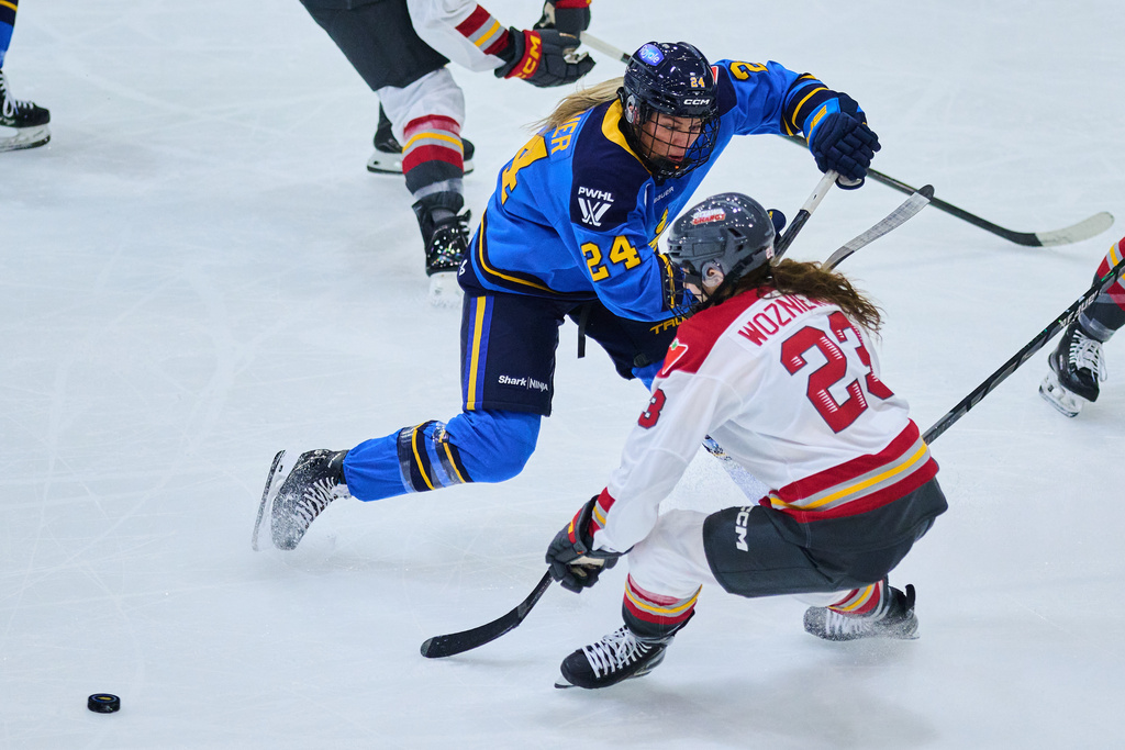 Toronto Sceptres' Natalie Spooner (24) and Ottawa Charge's Sarah Wozniewicz (23) battle for the puck during second period PWHL hockey action in Toronto, on Thursday, Dec. 4, 2025. (Sammy Kogan/The Canadian Press via AP)