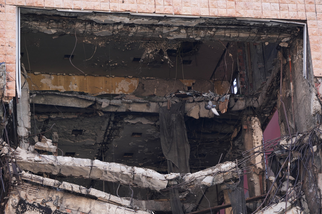 A pigeon flies through former Yugoslav army headquarters destroyed in a U.S.-led NATO bombing campaign in 1999, left, is seen in Belgrade, Serbia, Tuesday, Nov. 4, 2025. (AP Photo/Darko Vojinovic)