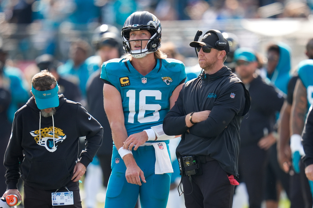 Jacksonville Jaguars quarterback Trevor Lawrence (16) stands next to head coach Liam Coen during the first half of an NFL wild-card playoff football game against the Buffalo Bills Sunday, Jan. 11, 2026, in Jacksonville, Fla. (AP Photo/John Raoux)