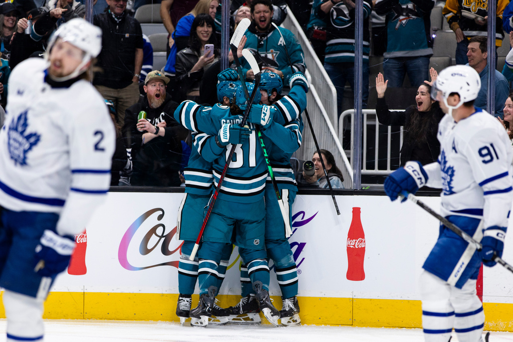 San Jose Sharks center Zack Ostapchuk, obscured, is congratulated by right wing Adam Gaudette (81) and teammates after he after scored a goal against the Toronto Maple Leafs during the first period of an NHL hockey game in San Jose, Calif., Thursday, April 2, 2026. (AP Photo/John Hefti)