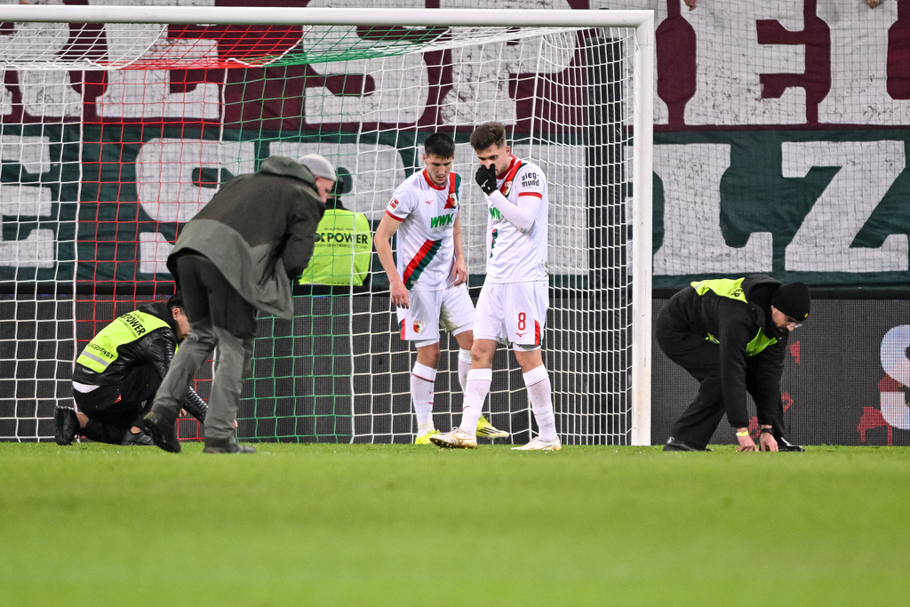 Players and stewards collect objects from the pitch during the Bundesliga soccer match between FC Augsburg and FC Union Berlin in Augsburg, Germany, Thursday Jan. 15, 2026. (Harry Langer/dpa via AP)