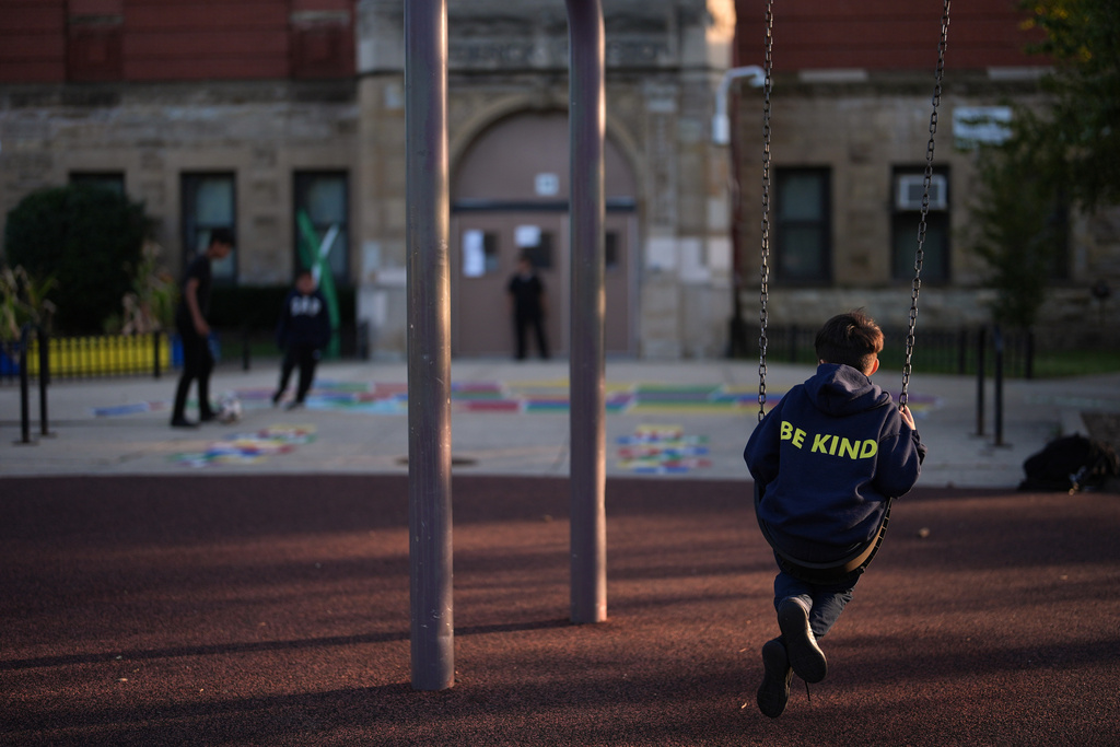 A boy wearing a Funston Elementary School sweatshirt printed with the motto "Be kind," swings on the playground as other kids play after school hours in Chicago's Logan Square neighborhood, Thursday, Oct. 16, 2025. (AP Photo/Rebecca Blackwell)