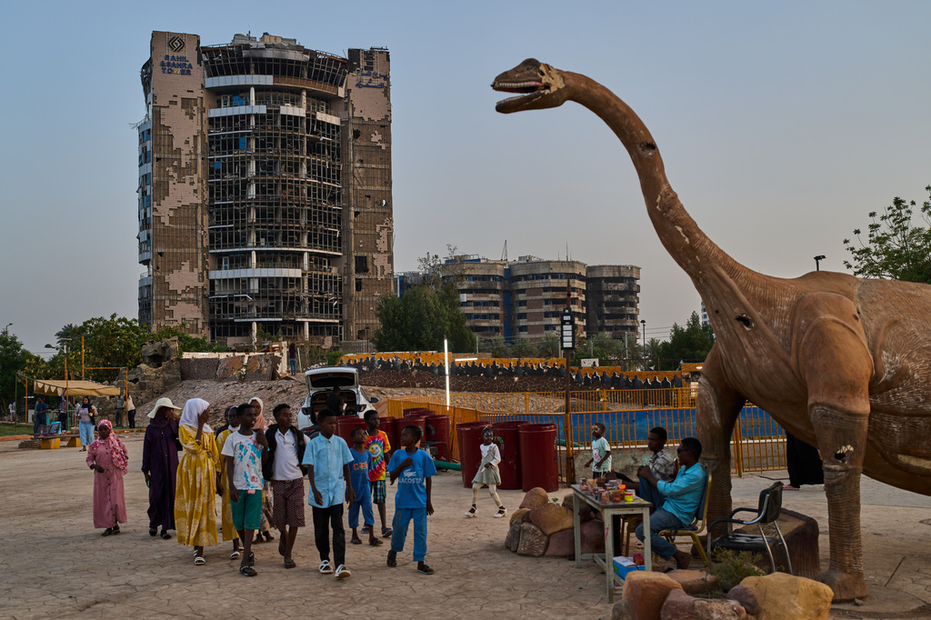Backdropped by a war-torn building, children enjoy an amusement park in downtown Khartoum, Sudan, Sunday, April 19, 2026. (AP Photo/Bernat Armangue)